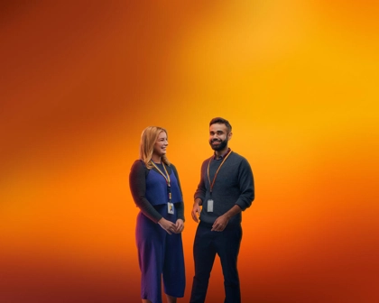 Duas pessoas com badges da GSK, fotografadas em fundo laranja